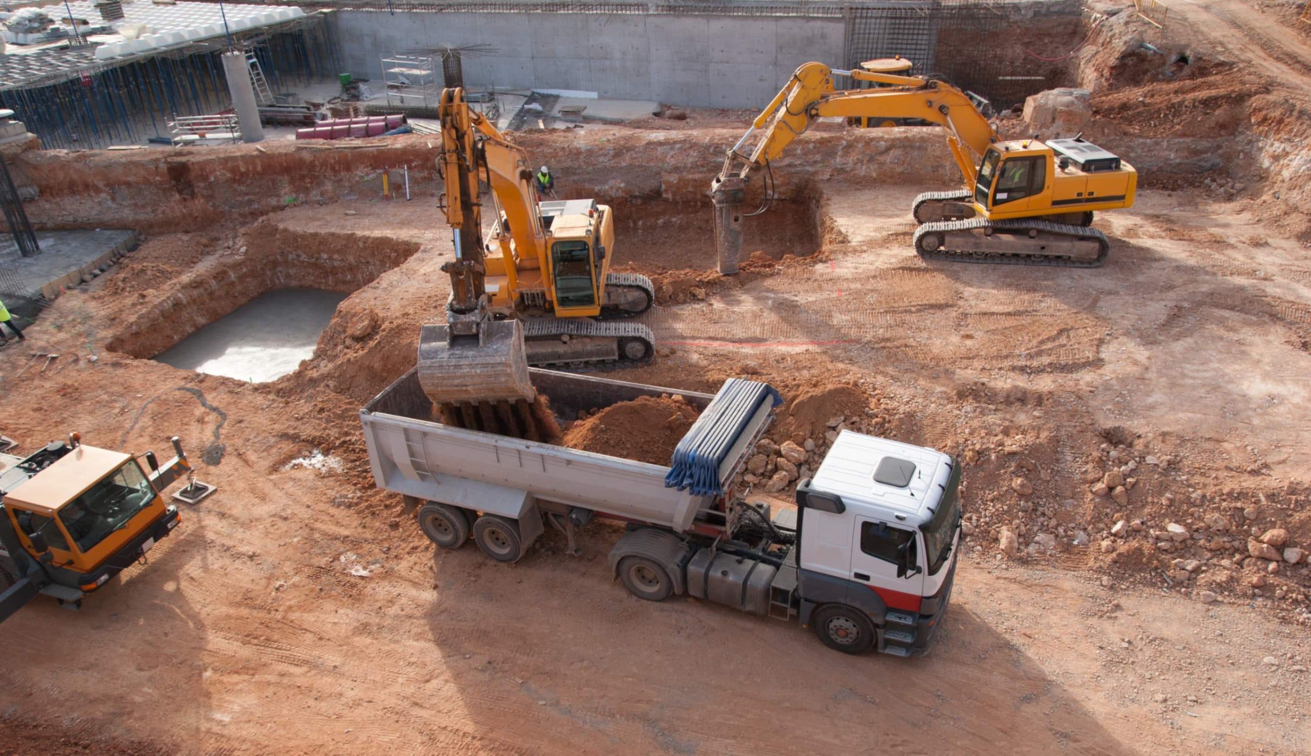 Excavators loading a tipper truck during bulk earthworks on a development site