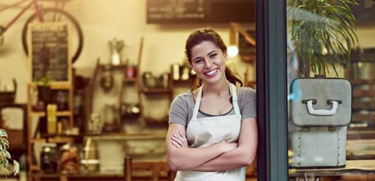Cafe owner in an apron standing in the doorway of her cafe
