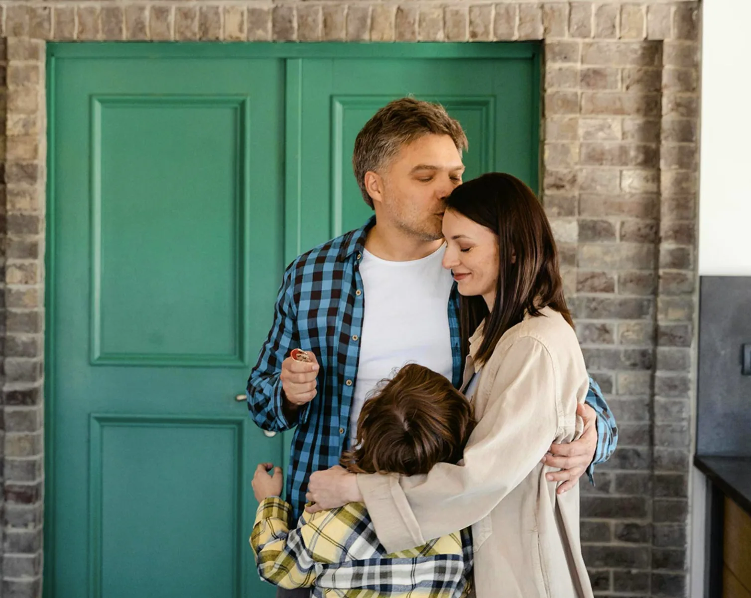 Family celebrating the keys to their new home in front of a green front door